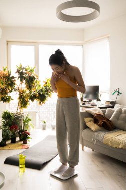 Evdeki terazide gülümseyen ve sevinen kadın.