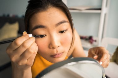 Kız makyaj yapmaya hazırlanırken aynanın karşısında oturuyor.