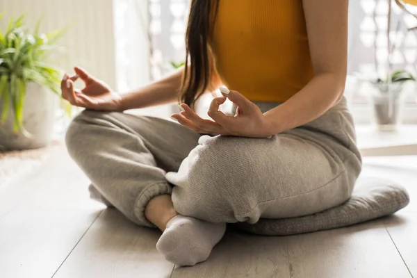 Dívka sedící se zkříženýma nohama na podlaze, cvičí jógu a užívá si meditace — Stock fotografie