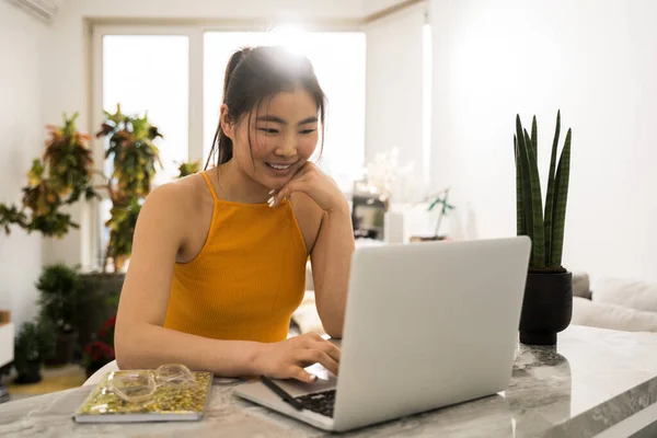 Mujer mirando a la pantalla del ordenador portátil con sonrisa mientras disfruta viendo webinar educativo —  Fotos de Stock