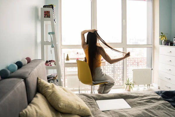 Vrouw borstelen haar haar met kam voor de wandeling, terwijl zitten in de slaapkamer — Stockfoto