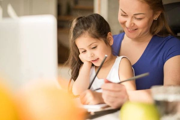 Anya és kislánya gyermek tanulás otthon, miközben web osztály a számítógépen — Stock Fotó