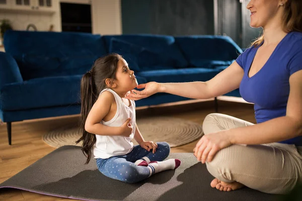 Mujer meditando en casa y practicando yoga mientras está sentada en el suelo con su hijo —  Fotos de Stock