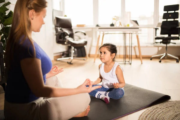 Mulher em roupas casuais meditando com sua filha e sentado em pose de lótus — Fotografia de Stock