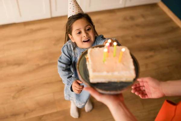 Chica con gorra de fiesta soplando las velas en su pastel de cumpleaños — Foto de Stock