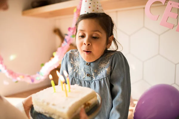 Chica con gorra de fiesta soplando en las velas en su pastel de cumpleaños — Foto de Stock