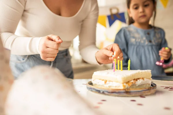 Mother lights the candles on the birthday cake while her daughter standing nearby — Φωτογραφία Αρχείου