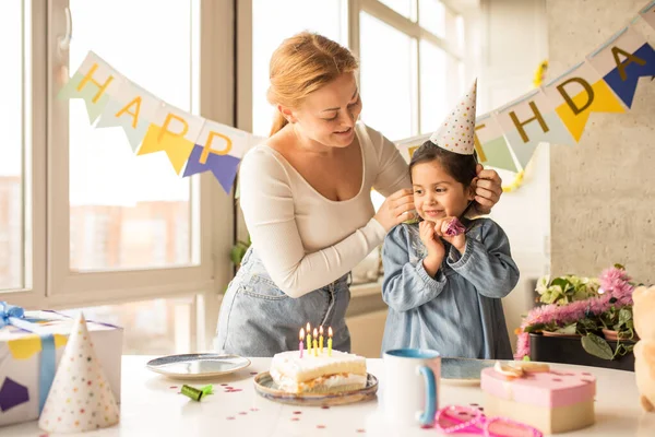 Mother straightens party cap on the head while her daughter standing at the table — Φωτογραφία Αρχείου