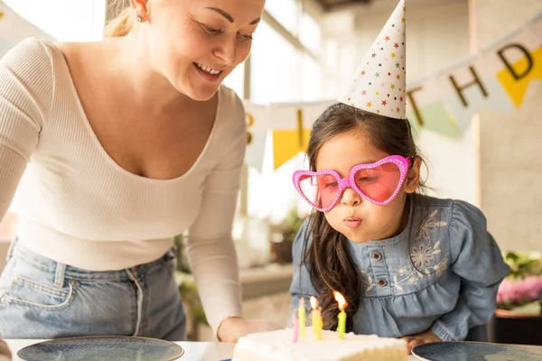 Girl wearing funny glasses blowing candles at the birthday cake while celebrating — Φωτογραφία Αρχείου