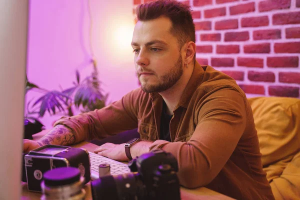 Fotógrafo sentado en la mesa después de disparar y trabajar con las fotos — Foto de Stock