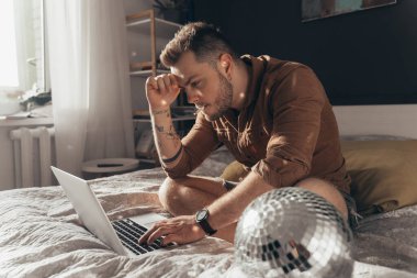 Adam dizüstü bilgisayarda oturup marihuana içerken bir şeyler yazıyor.