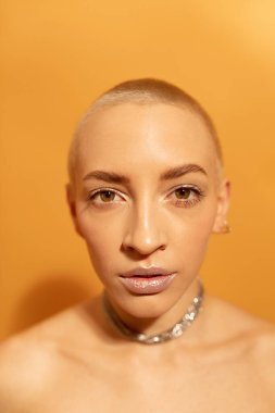 Kısa saçlı ve makyajlı ciddi bir kadın kameradan tatmin olmuş görünüyor.