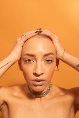 Elleri başının üstünde poz veren ve kameraya bakan bir kadın.