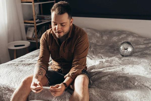 Mannen som sitter i sovrummet och förbereder handrullad cigarett — Stockfoto