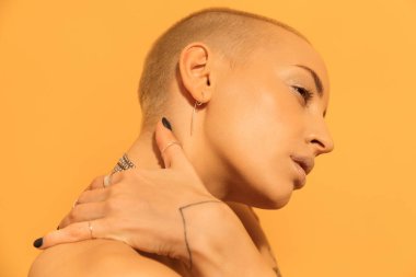 Çıplak omuzlu bir kadın poz verirken elini boynundan tutuyor.