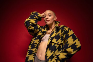 Kısa saçlı kadın poz verirken kameraya zevkle bakıyor.