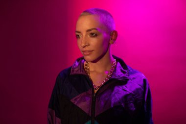 Kısa saçlı kadın ayakta duruyor ve hayattan zevk alırken gözlerini kaçırıyor.