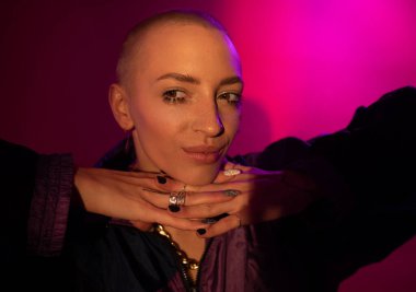 Yüzüne yakın ellerle kameraya poz verirken gülümseyen siyah gözlü kadın.