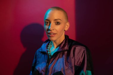 Makyajlı ve kısa saçlı bir kadın kameraya bakıyor.