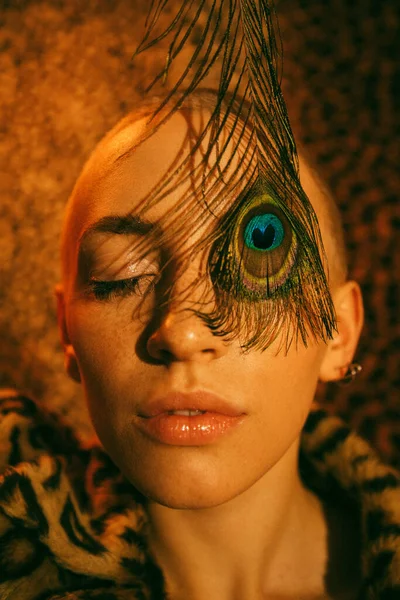 Kvinna med fräknar hud gömmer ögat bakom påfågeln läder medan poserar — Stockfoto