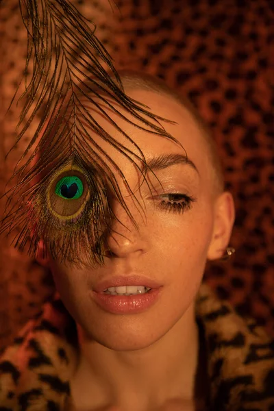 Girl hiding her eye behind the peacock leather — Stock Photo, Image