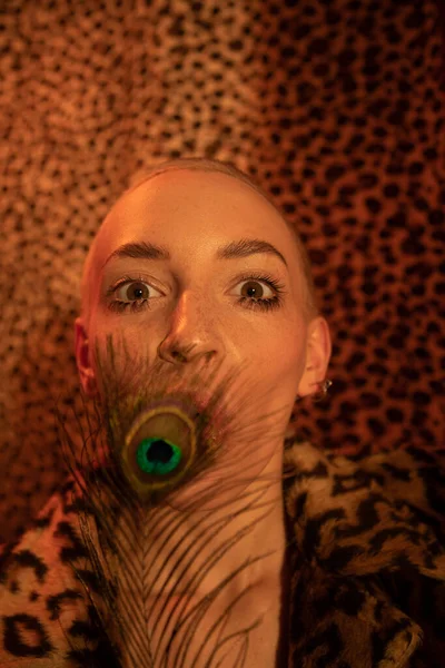 Kvinna gömmer sitt ansikte bakom påfågeln läder medan poserar med öppen mun — Stockfoto