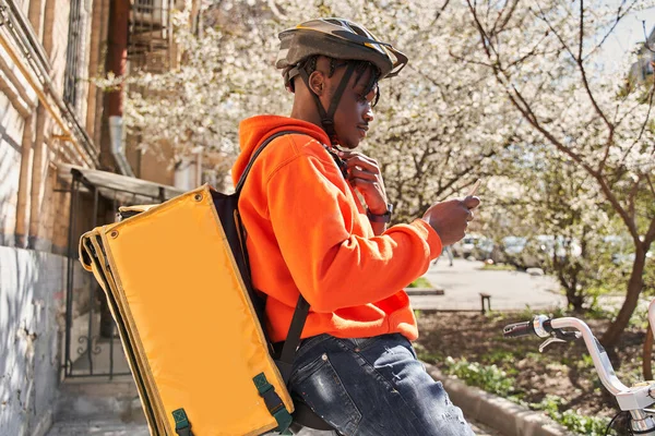 Человек курьер с помощью карты приложение на мобильном телефоне, чтобы найти адрес доставки — стоковое фото