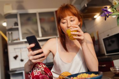 Masada kahvaltı ederken akıllı telefonundan bir şey izleyen bir kadın.