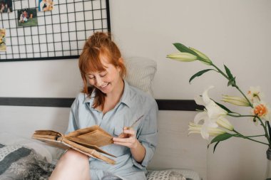 Hafta sonunu kitap okuyarak geçirirken gülümseyerek geçiren genç bir kadın.