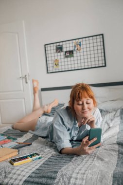 Evde dinlenen, cep telefonu tutan ve selfie çeken bir kız.