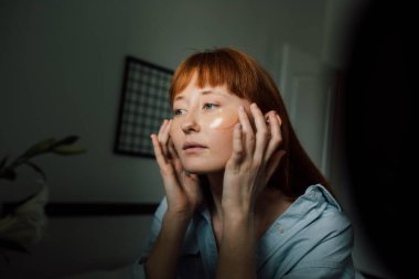 Kızıl kadın sabah yüzüne yamalar yapıştırıyor.