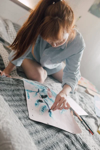Žena se dívá na svůj obraz doma, zatímco kreslí pastelkami — Stock fotografie