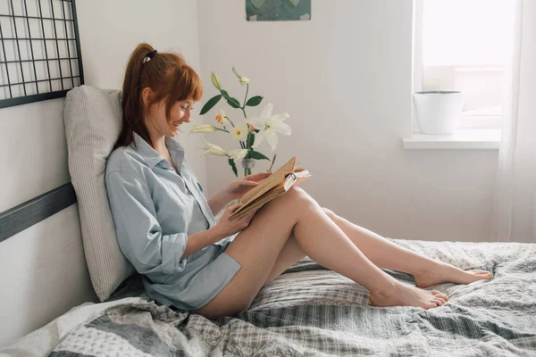 Mujer leyendo libro con sonrisa de placer mientras pasa su fin de semana —  Fotos de Stock