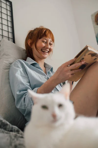 Žena se hlasitě směje, zatímco si užívá volného víkendu s oblíbeným románem — Stock fotografie