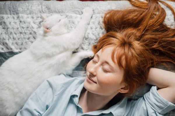 Mujer acostada en la cama y unida a su gato blanco mientras pasa la mañana —  Fotos de Stock