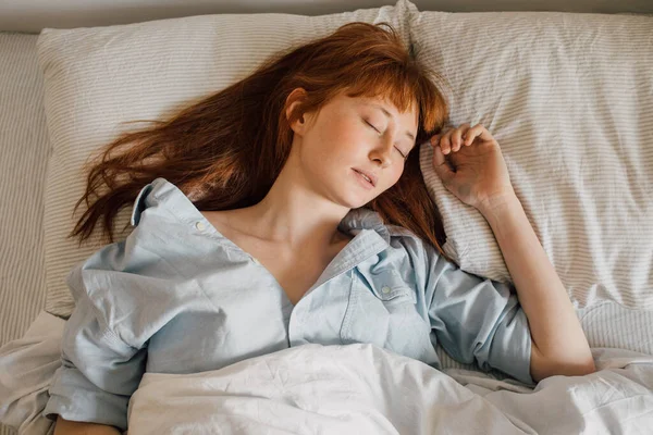 Frau liegt im Bett und hält Augen zu, während sie mit Decke bedeckt ist — Stockfoto