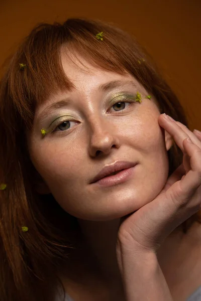 Vrouw met bloemen in haar gezicht en haar en kijkend naar de camera — Stockfoto