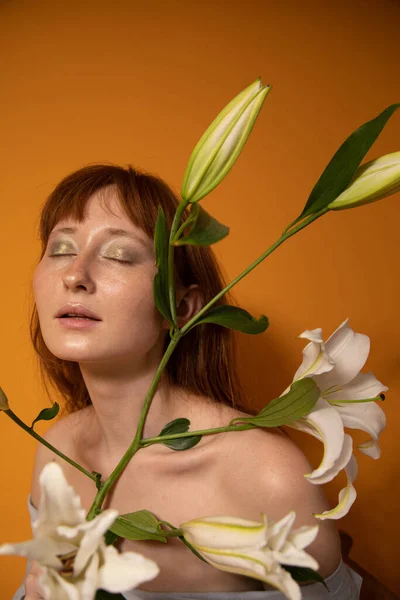 Vrouw met groene ogen sloot haar ogen en hield lelies vast terwijl ze poseerde — Stockfoto