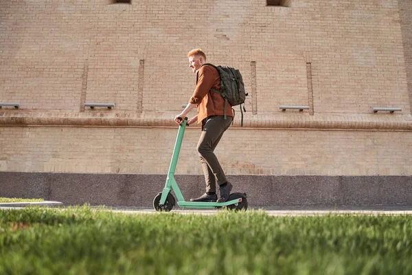 Man met rugzak is met behulp van scooter en rijden door de stedelijke weg — Stockfoto