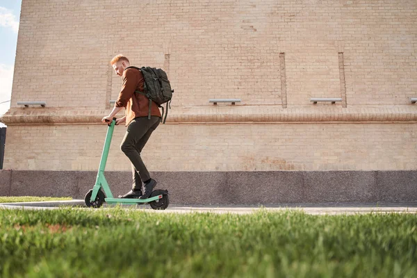 Uomo freelance indossare zaino a piedi con scooter sulla strada della città — Foto Stock