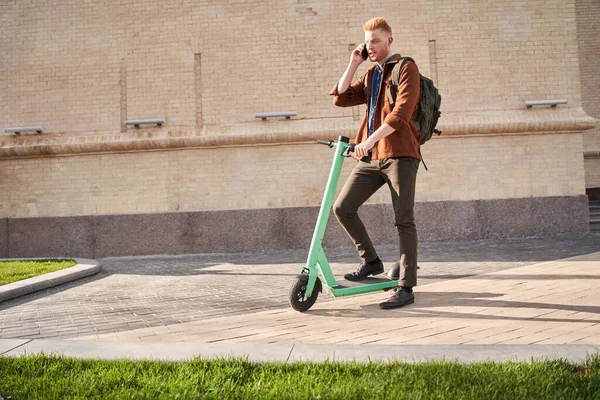 Man met rugzak rijden op elektrische scooter op straat en chatten — Stockfoto
