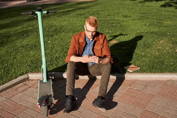 Manliga bär glasögon skriva i mobiltelefon medan du tittar på gadget skärmen — Stockfoto