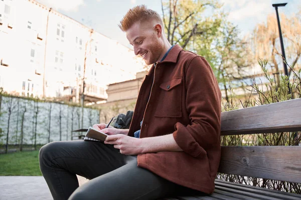 Man är djupt på sitt arbete medan man sitter vid bänken och gör några anteckningar — Stockfoto