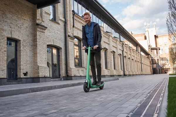 Man gaat ergens met een ecologische elektrische scooter door de stedelijke straat — Stockfoto