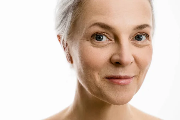 Mulher com pele de rosto macio perfeito olhando para a câmera e sorrindo ao posar — Fotografia de Stock