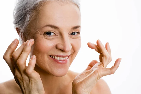 Mujer madura sonriendo con la mano cerca de su cara — Foto de Stock