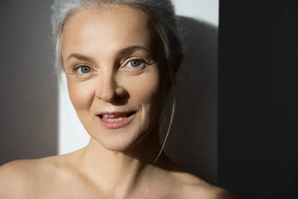 Mulher sênior olhando para a câmera com sorriso claro enquanto posando no estúdio — Fotografia de Stock