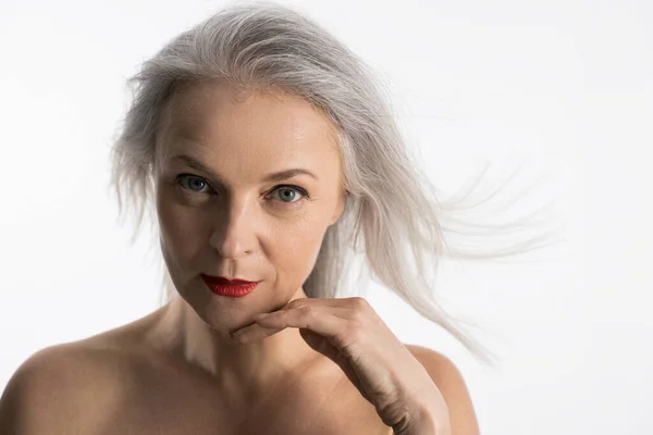 Woman with grey hair and bare shoulders looking thoughtfully at the camera — Stock Photo, Image