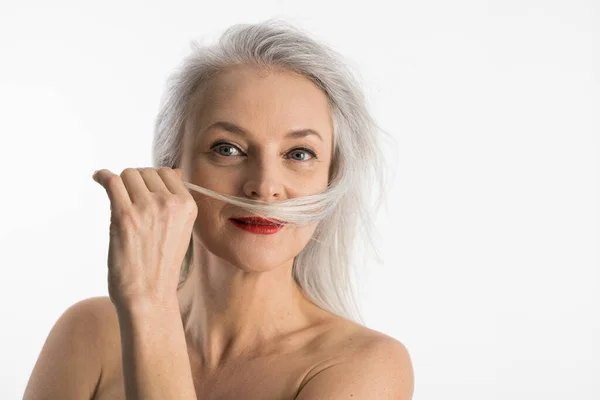 Vrouw staan geïsoleerd op witte achtergrond en aanraken van haar haar — Stockfoto