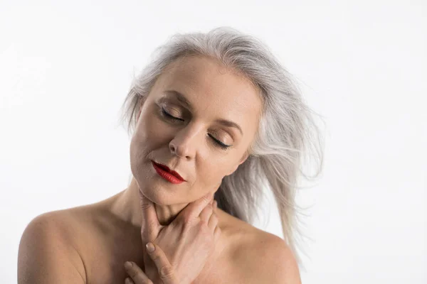 Жінка середнього віку торкається її здорової м'якої шкіри шиї і позує закритими очима — стокове фото